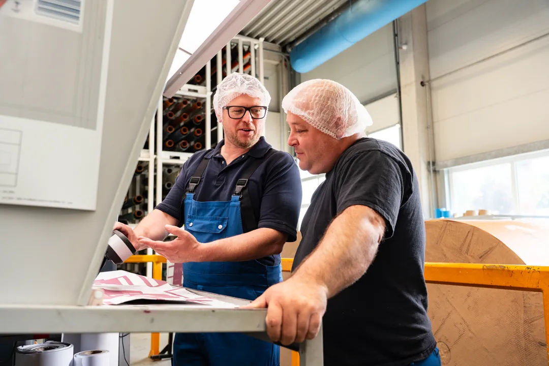 Zwei Mitarbeiter im Gespräch an der Druckmaschine